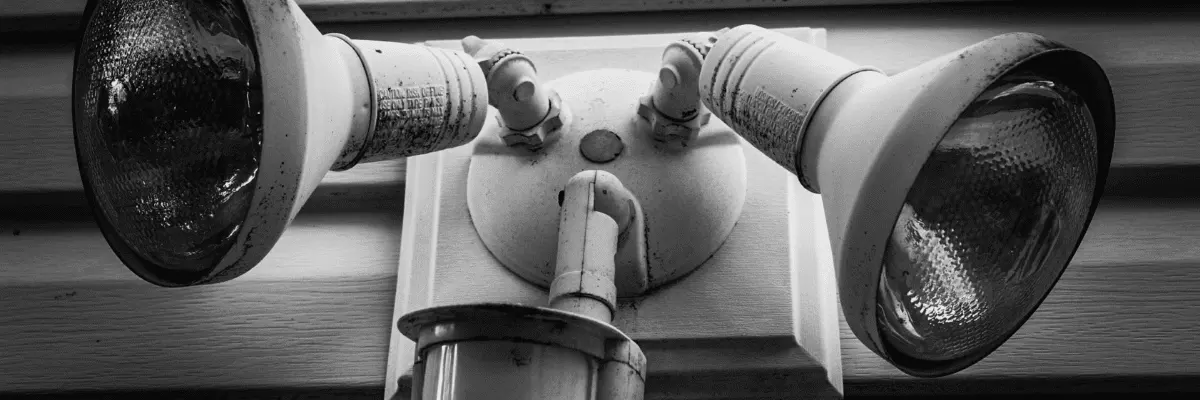 home security lights in black and white on a wooden panel exterior wall.
