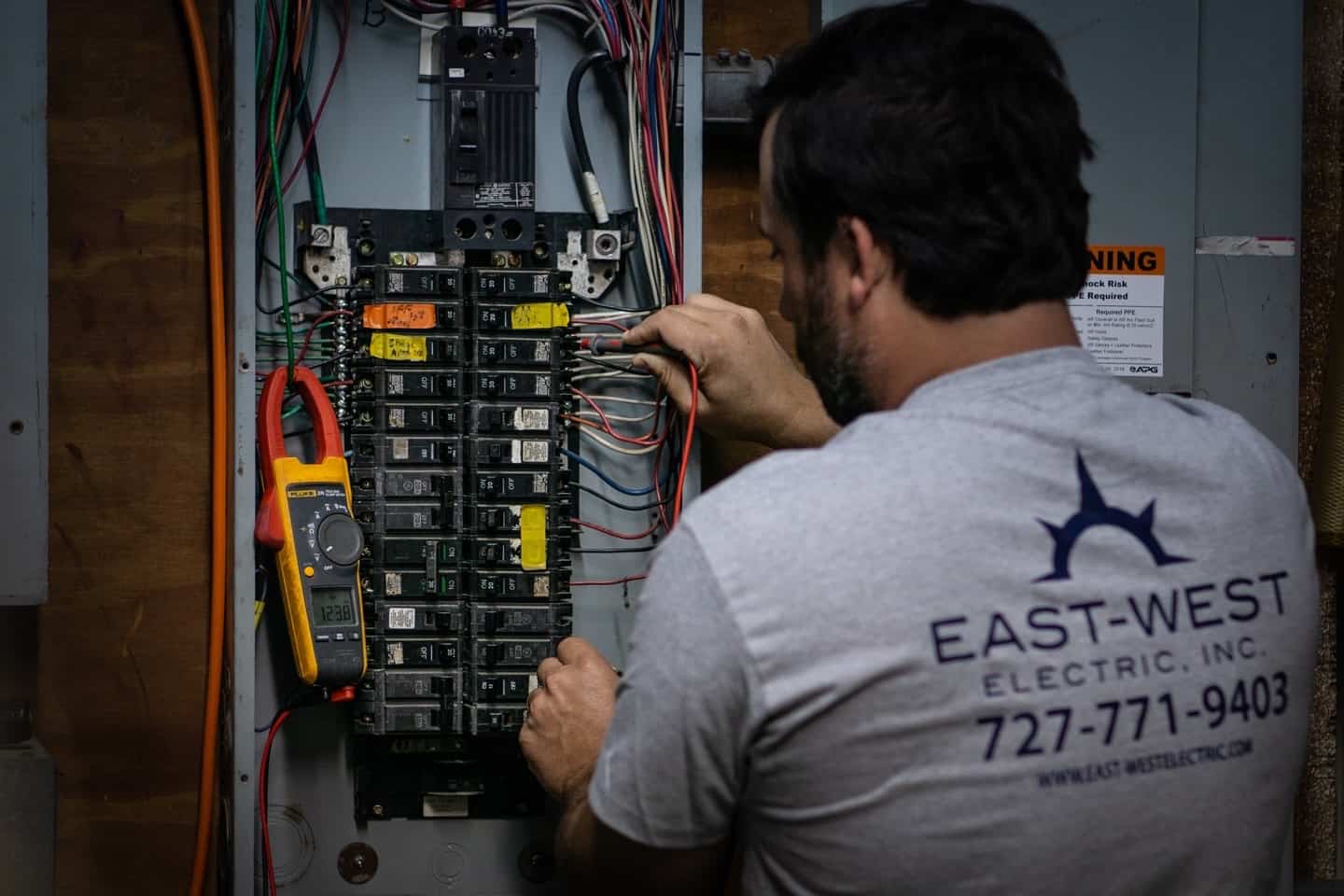 East-West electrician inspecting a commercial breaker panel